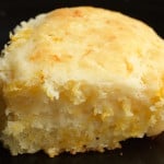 A thick cheesy buttermilk biscuit on a black background