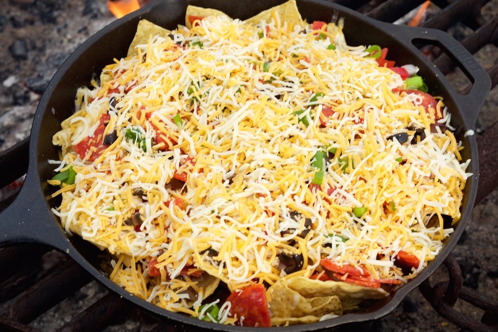 Shredded cheese and toppings on top of Campfire Pizza Nachos before it is melted.
