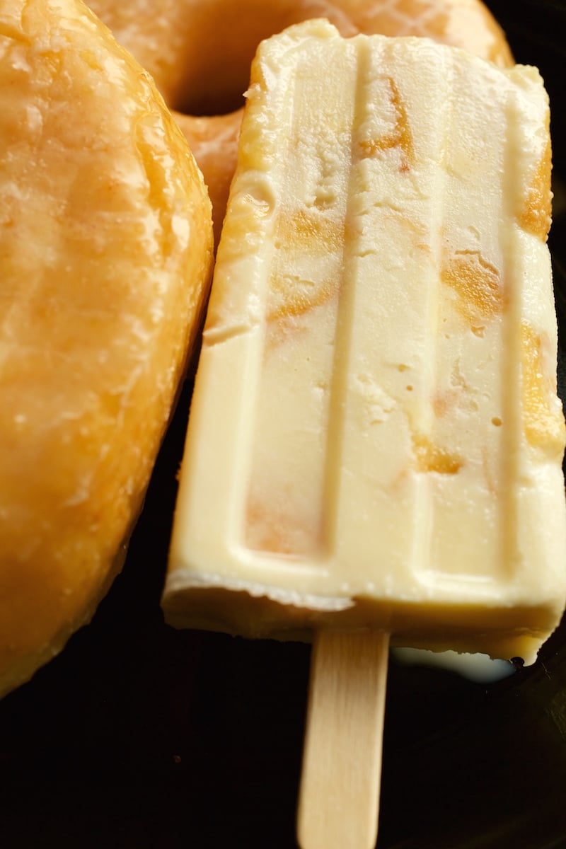 Close up of a Donuts & Milk Popsicle on a dark background.