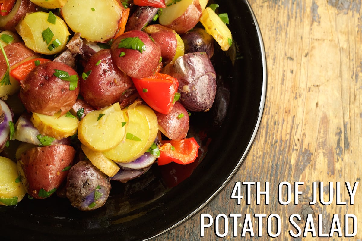 A plate of multi colored potato salad. Text in the left hand corner reads "4th Of July Potato Salad".