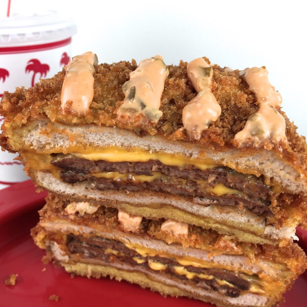 A close up of a fried In-N-Out Burger that's been cut in half, then stacked on top of each other. The breading is topped with lines of special sauce.
