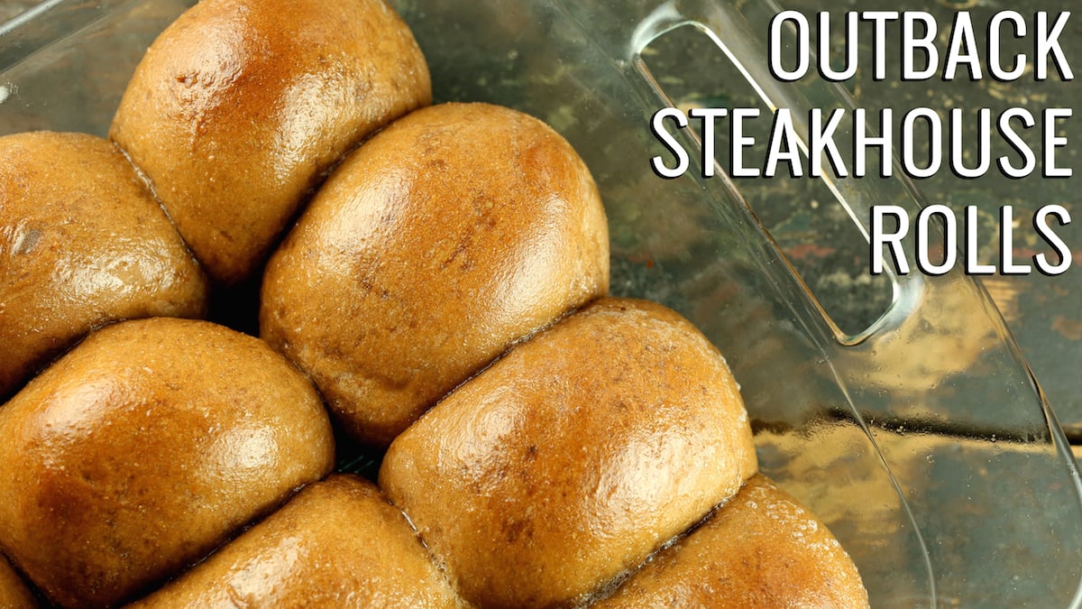 Close up of brown rolls in a glass casserole dish. Text reads "Outback Steakhouse Rolls"