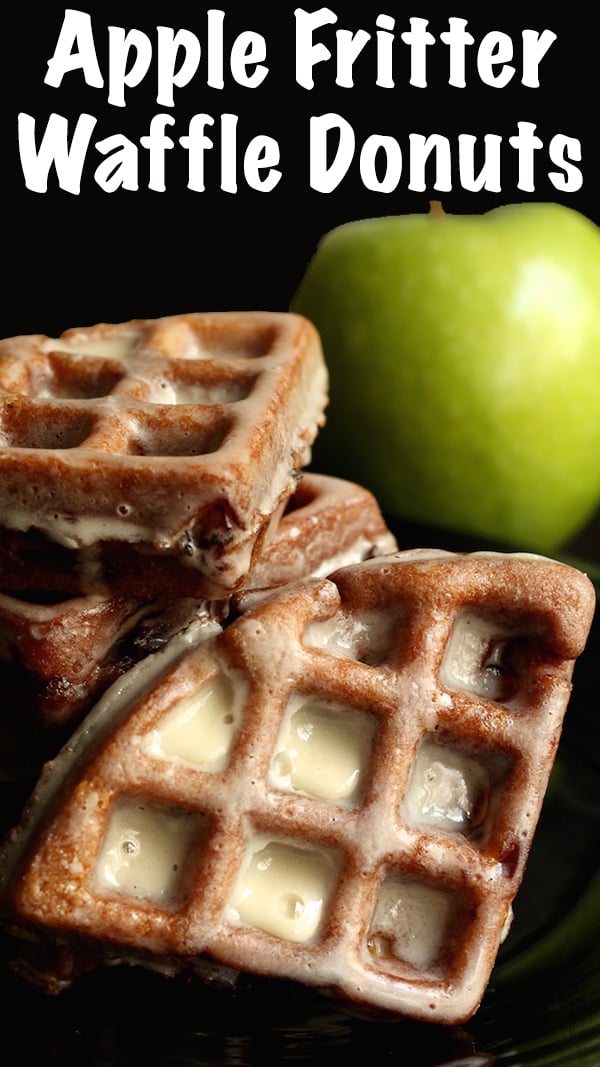 Apple Fritter Waffle Donuts stacked up on top of each other. A green apple is out of focus in the background.