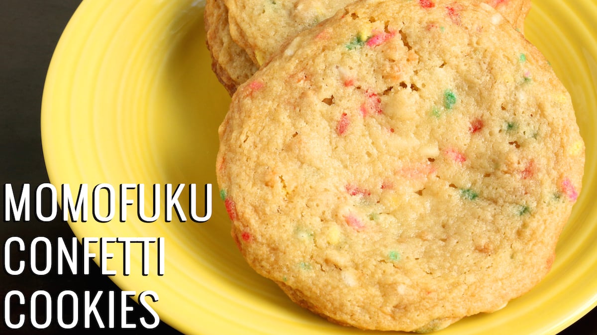 A photo of large cookies with sprinkles baked in the batter on a yellow plate. Text reads "Momofuku Confetti Cookies"