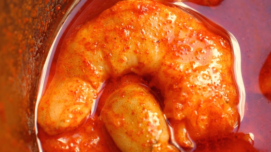Close up of a single shrimp in red sauce.