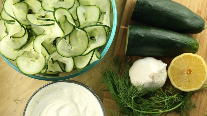 Overhead view of Cucumber Tzatziki Salad ingredients: spiralized cucumber, dill, lemon, garlic, and yogurt.