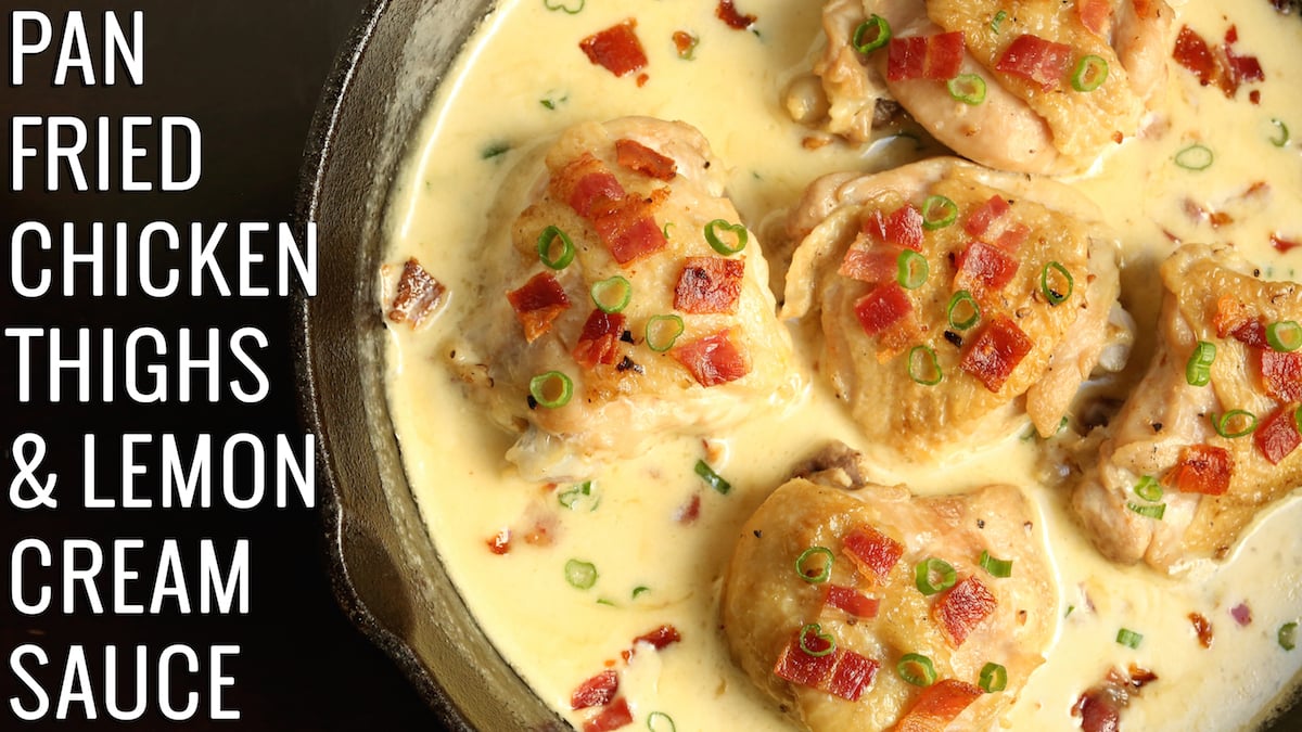 A cast iron skillet filled with browned chicken thighs in a yellow sauce. Text reads "Pan Fried Chicken Thighs & Lemon Cream Sauce"
