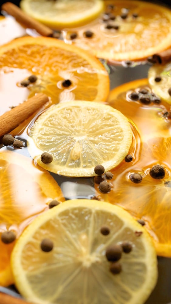 Close up of lemon and orange slices floating on top of a crock pot of apple cider. 