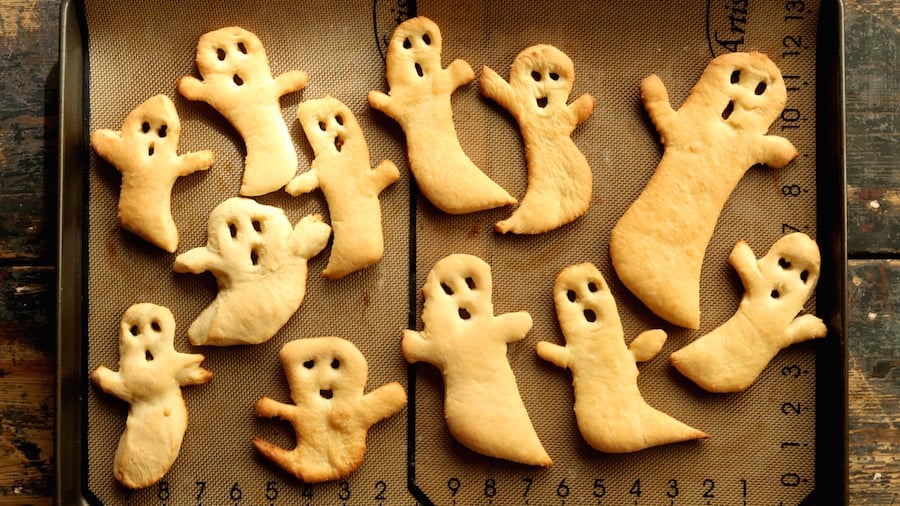 A dozen Halloween Ghost Crisps on a baking sheet with a silicone mat.