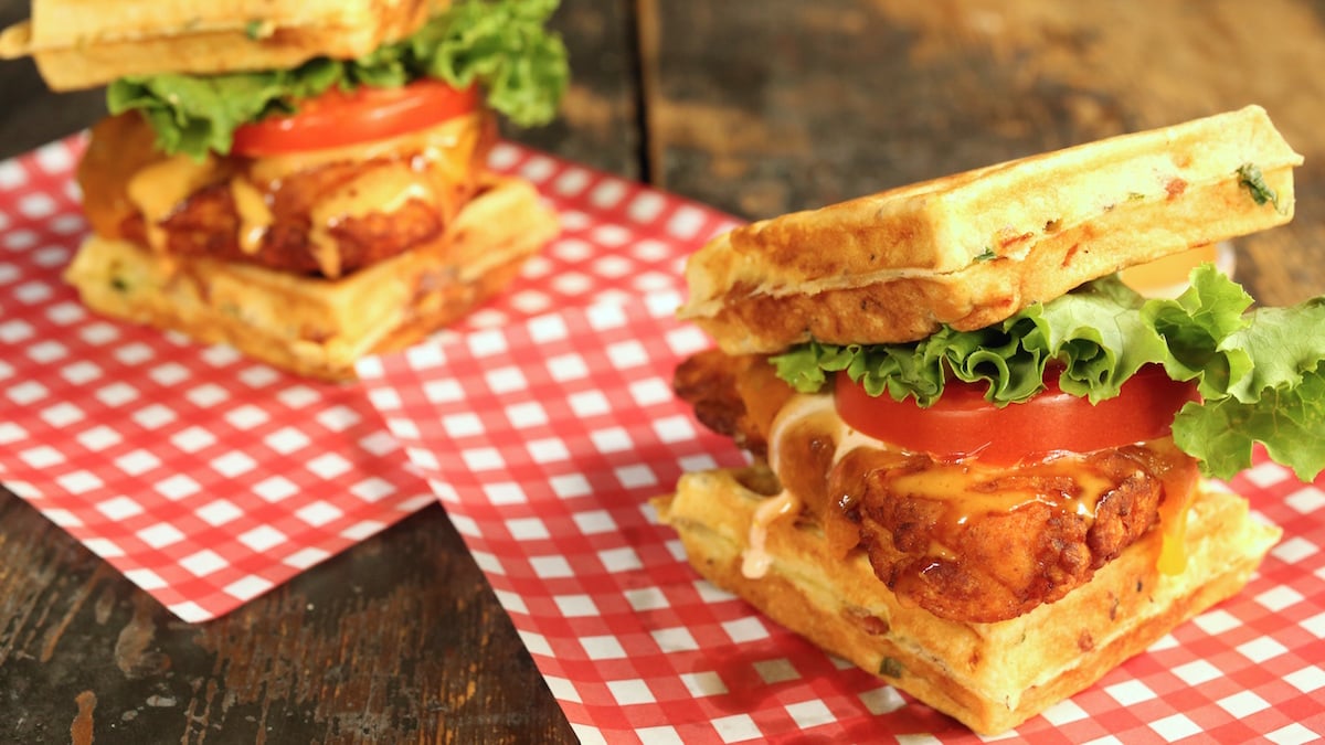 Buttermilk Fried Chicken Cheddar Bacon Waffle Sandwiches on plaid sandwich paper.