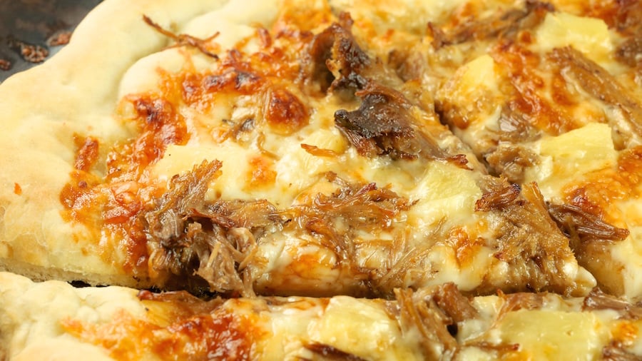 Close up of a slice of Kalua Pork Pizza on a pizza stone.