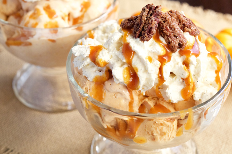 A large glass ice cream sundae bow filled with Pumpkin Pie Ice Cream Maple Vanilla Bourbon Whipped Cream, Pumpkin Caramel, and Candied Pecans