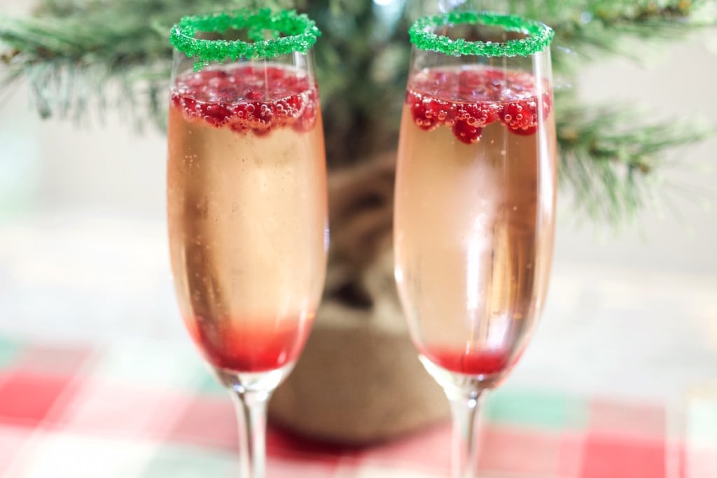 Two Christmas Champagne Cocktails in champagne flutes in front of a mini Christmas tree.
