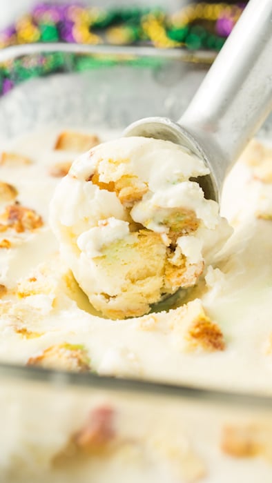 Homemade king cake ice cream being scooped out of a shallow glass pan