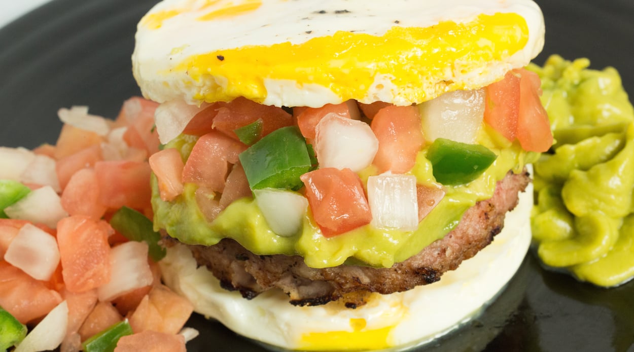  A homemade pork sausage patty sandwiches between two eggs topped with pico de gallo