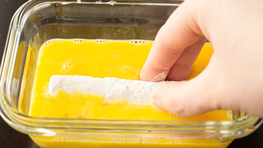 The stick that's been rolled in flour now being dipped in egg