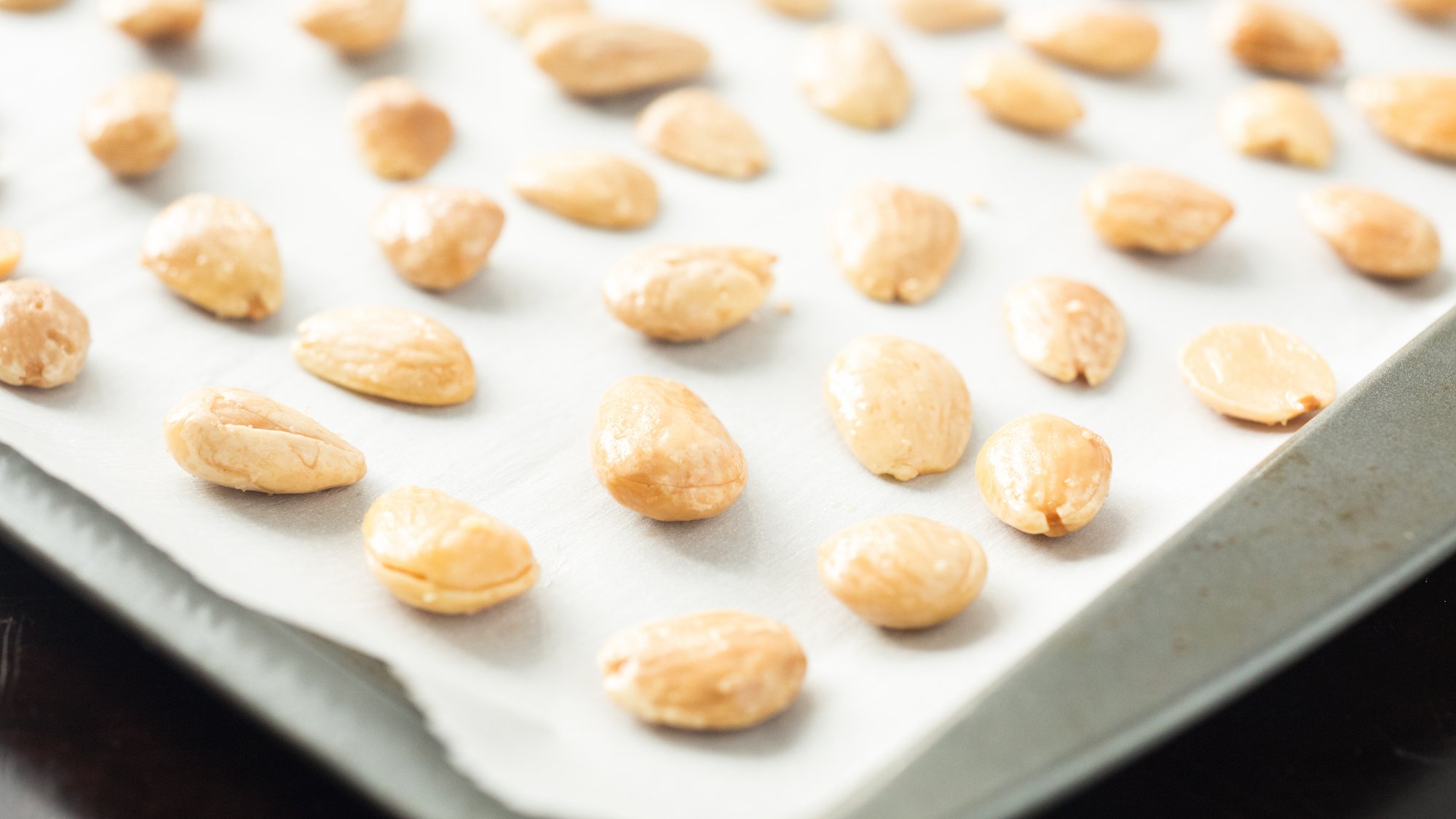 Marcona almonds arranged on parchment paper on a baking mat
