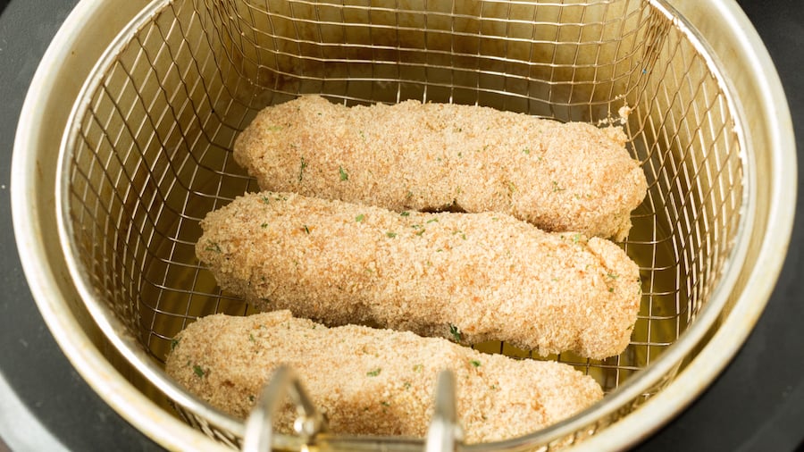 Mozzarella chicken cheese sticks on the deep fryer basket before being cooked