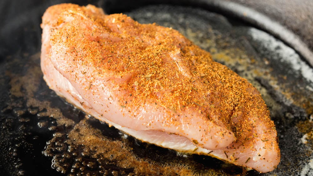 Blackened chicken being seared in the cast iron skillet.