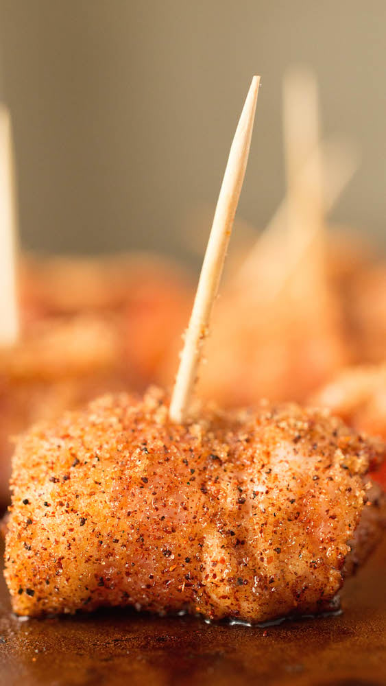 Close up of bacon wrapped chicken bites on toothpicks.
