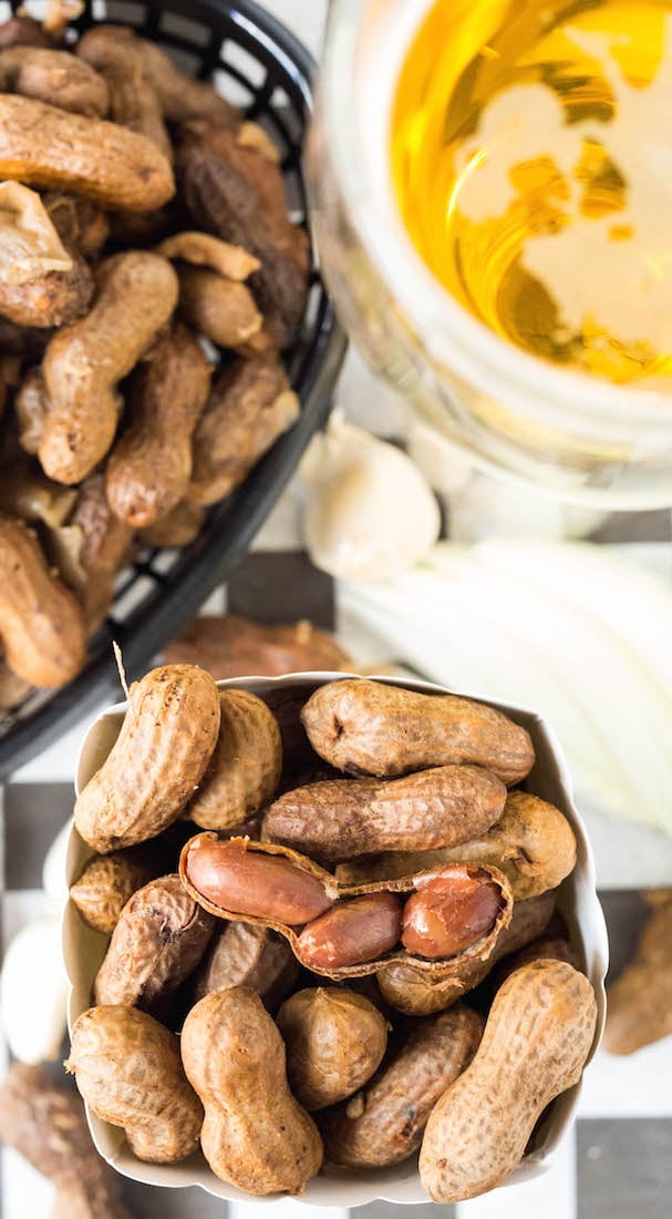 An overhead view of crock pot beer boiled garlic and onion peanuts next to a pint of beer.