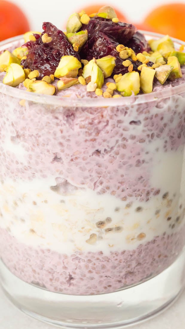 Close of of the parfait showing the layers of chia seed pudding, vanilla overnight oats, and chipped pistachio bee pollen toppings.