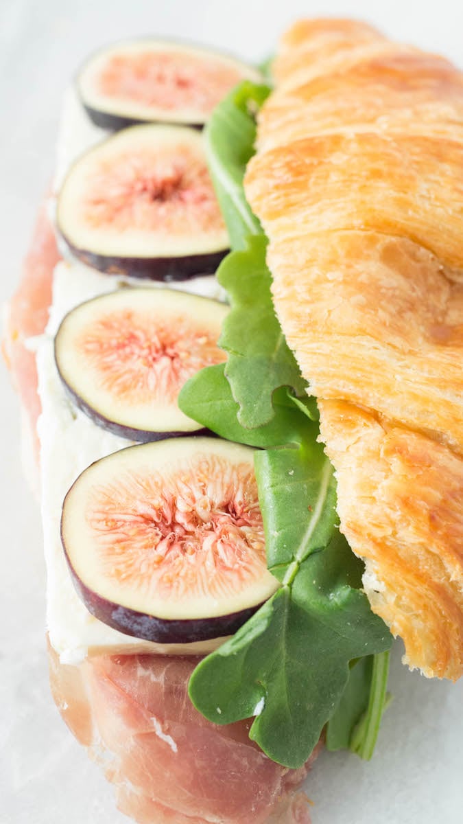 Close up of a croissant sandwich recipe made with figs, blue cheese, prosciutto, and arugula.