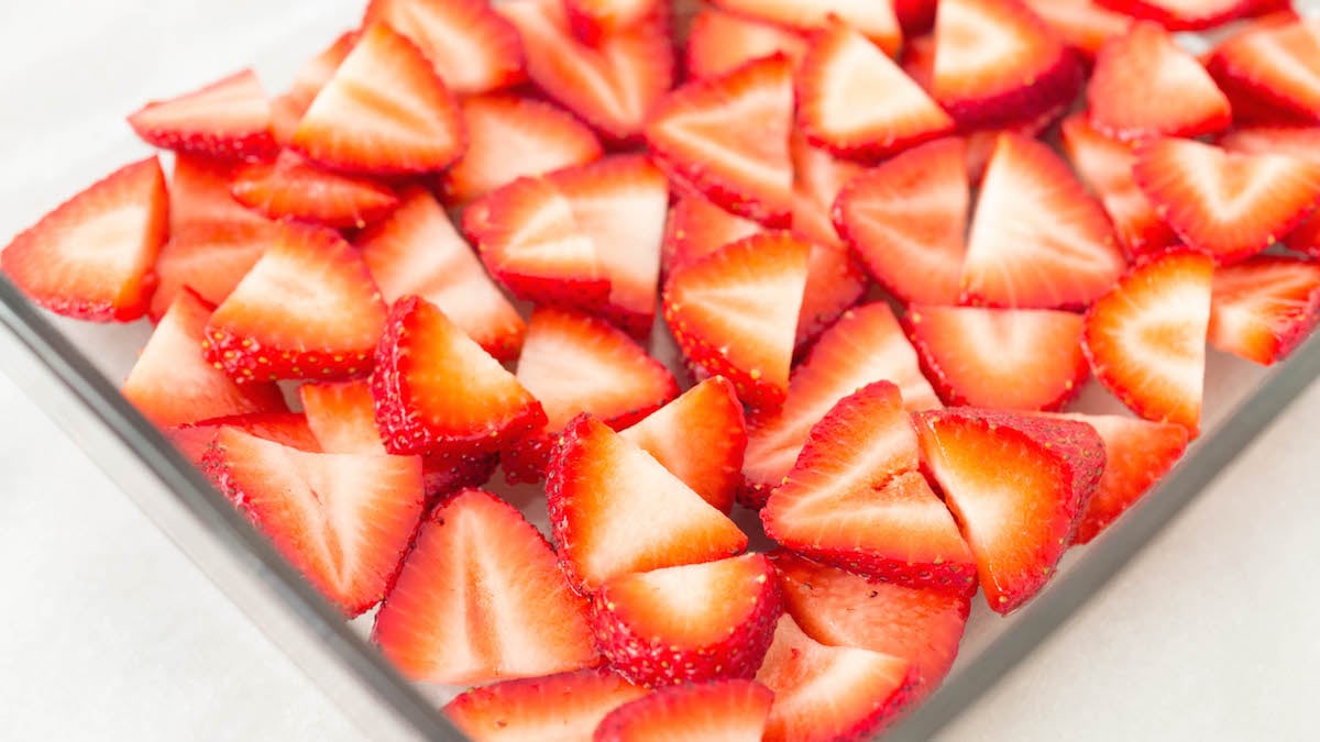 Overhead view of a glass baking pan filled with sliced strawberries.