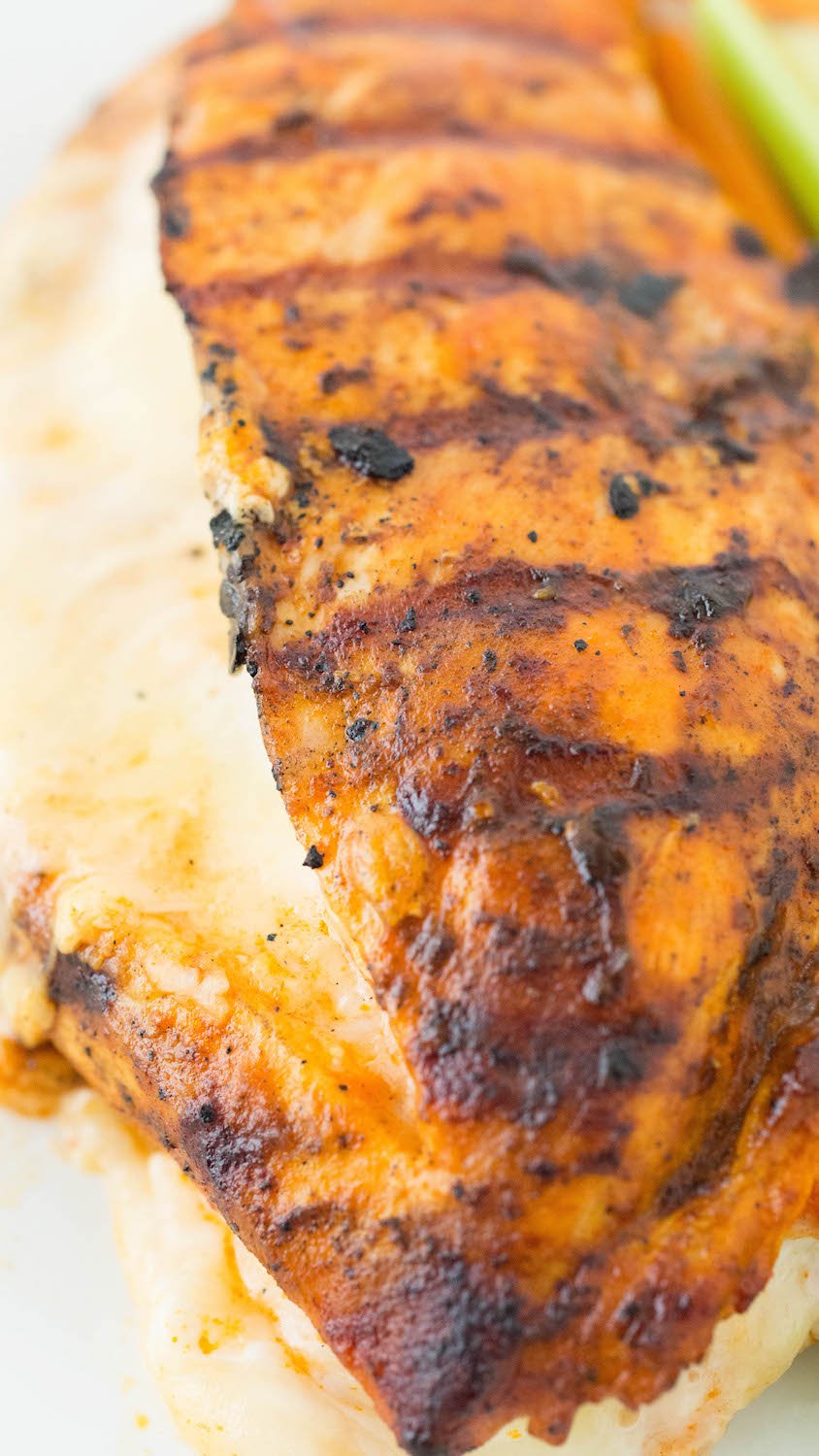 Close up of the top of a buffalo grilled chicken breast. Mozzarella cheese is oozing out of the side.