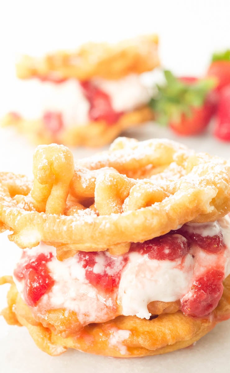 Close up of a funnel cake ice cream sandwich that's been filled with strawberry ice cream and strawberry syrup.