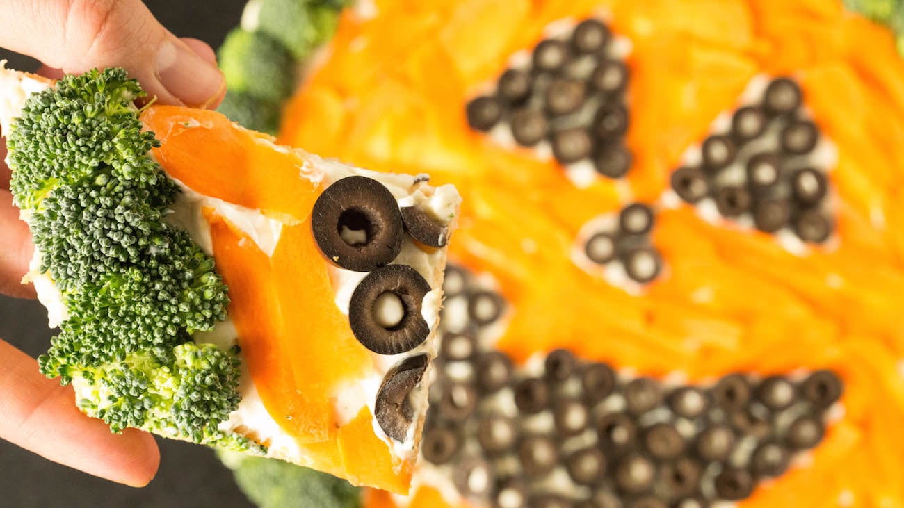 A cold Jack o' lantern "pizza" made of shaved carrots, olives, and broccoli.