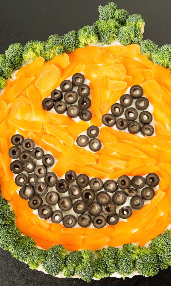 A smiling vegetable pizza that looks like a jack o' lantern. 