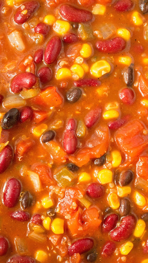 Close up view of meatless quinoa chili showing the individual ingredients like red beans, black beans, corn, diced onions, tomato, and peppers.