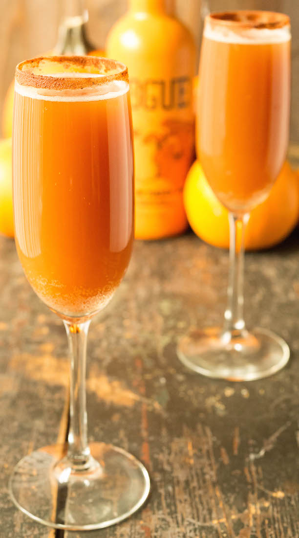 Two champagne flutes filled with orange pumpkin beermosas.