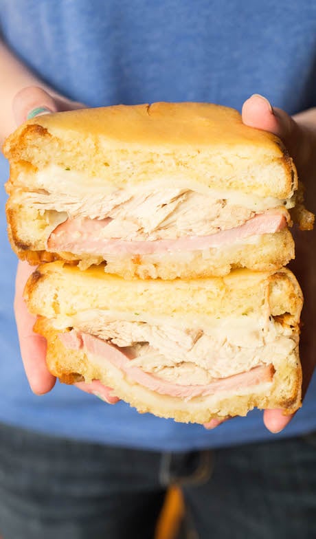 A Monte Cristo sandwich made with Thanksgiving leftovers has been sliced in half and is being held up by a pair of hands.