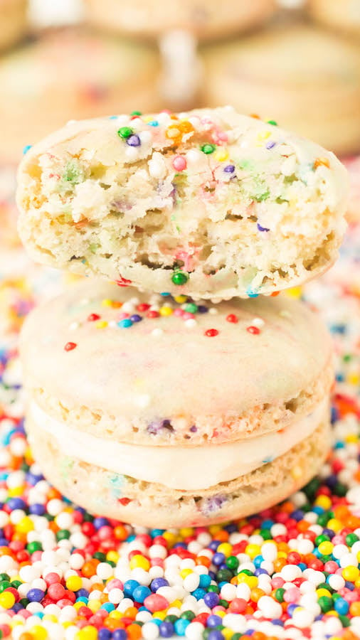 Two funfetti macaroons stacked on top of each other. One has a bite taken out of it.