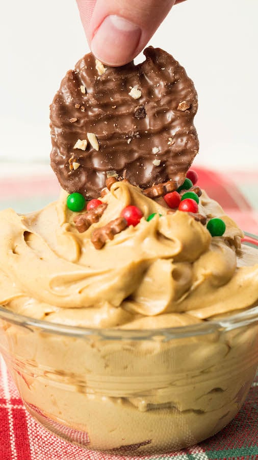 A chocolate potato chip being dipped into gingerbread dip.