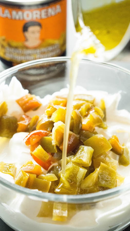 Canned jalapeño juice being poured into sour cream.