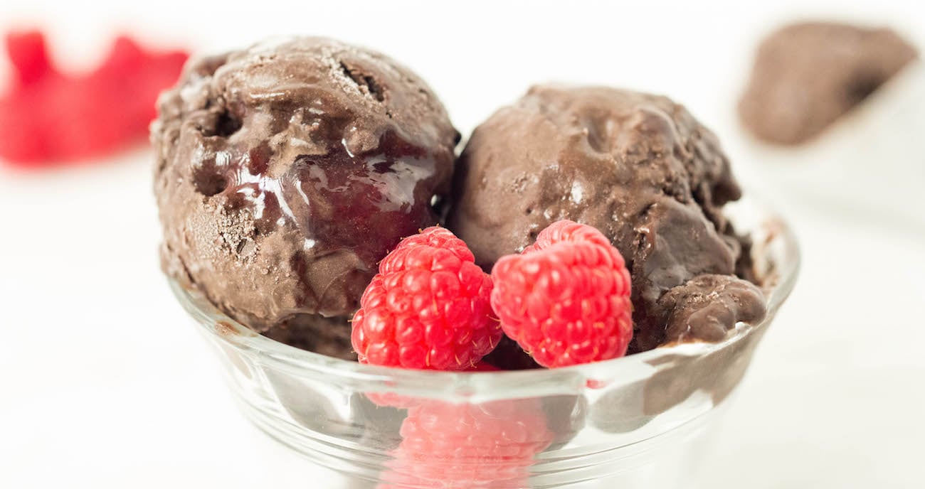 Two scoops of homemade Dark Chocolate Raspberry Gelato in a clear bowl garnished with raspberries.