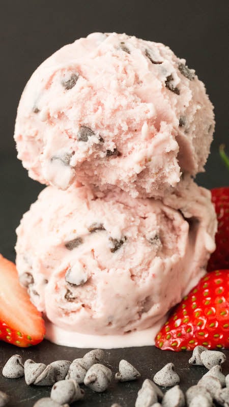 Two scoops of pink Strawberry Chocolate Chip Gelato are stacked on top of one another on a black background.