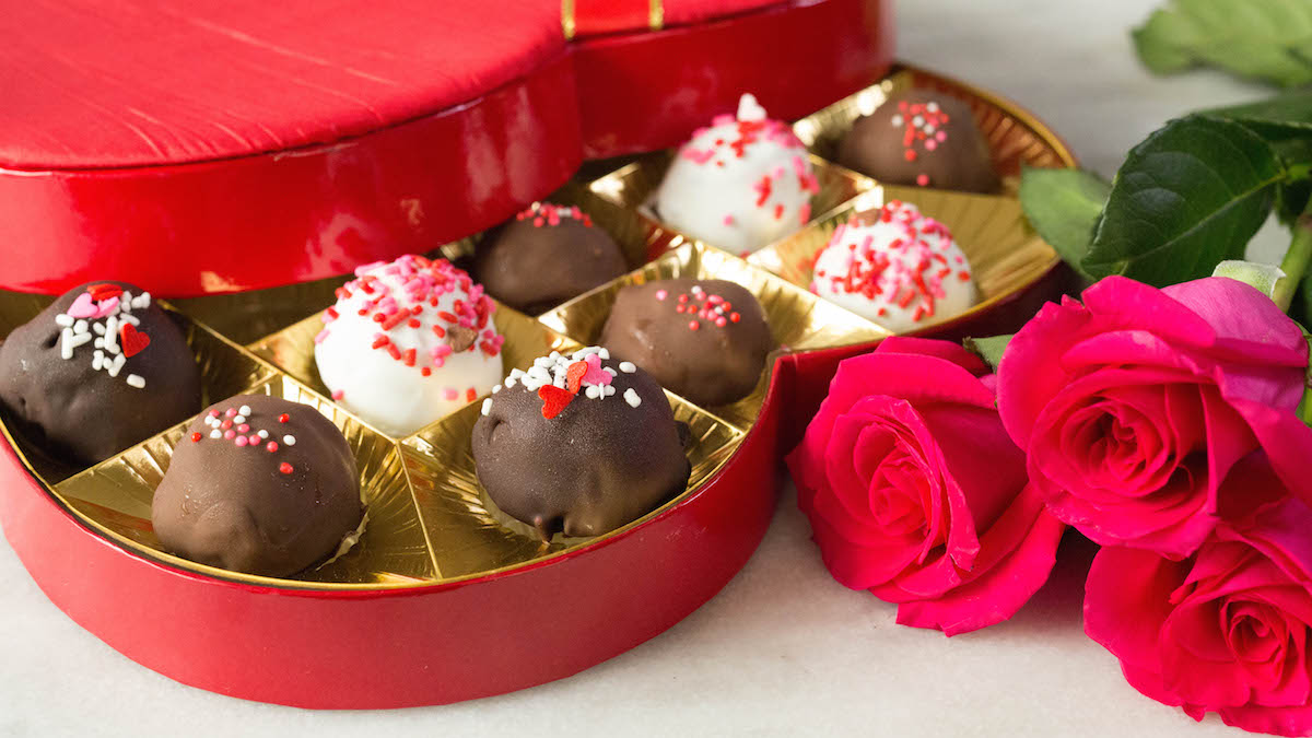 A heart chocolate box filled Valentine's Day Ice Cream Gelato Truffles next to roses.