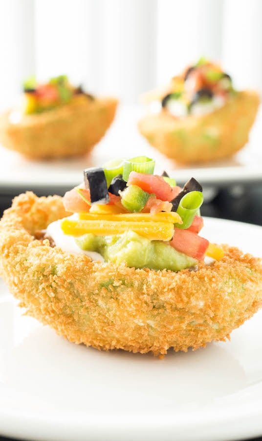 An avocado that has been sliced in half, breaded, deep fried then stuffed with 7 layer dip.