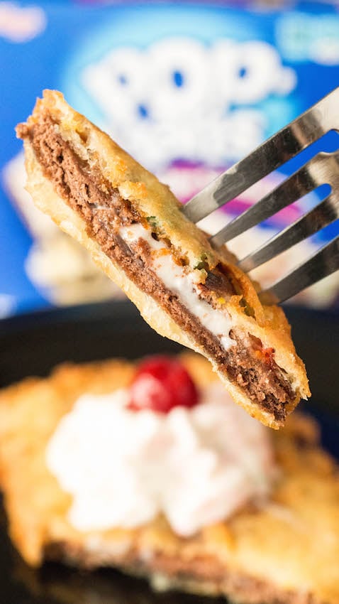 A fork holds up a piece of a deep fried pop-tart that shows the warm filling oozing out.