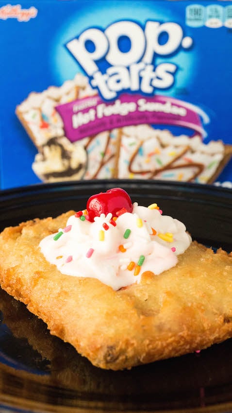 Close up of a homemade deep fried pop-tart that has been topped with whipped cream, sprinkles, and a cherry.