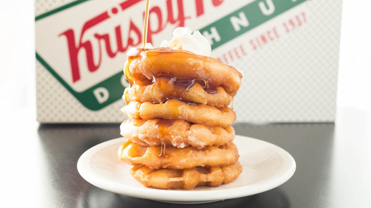 A stack of Krispy Kreme Glazed Donut Waffles in front of a Krispy Kreme box.
