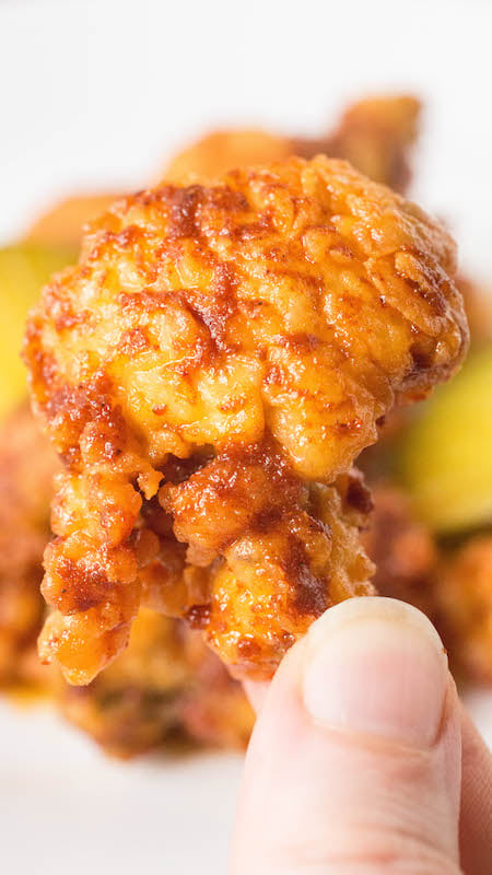 Close up of a finger holding a Nashville Hot Fried Oyster
