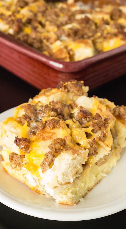 A slice of Sausage Egg McMuffin Casserole in front of the dish with the rest of the breakfast casserole.