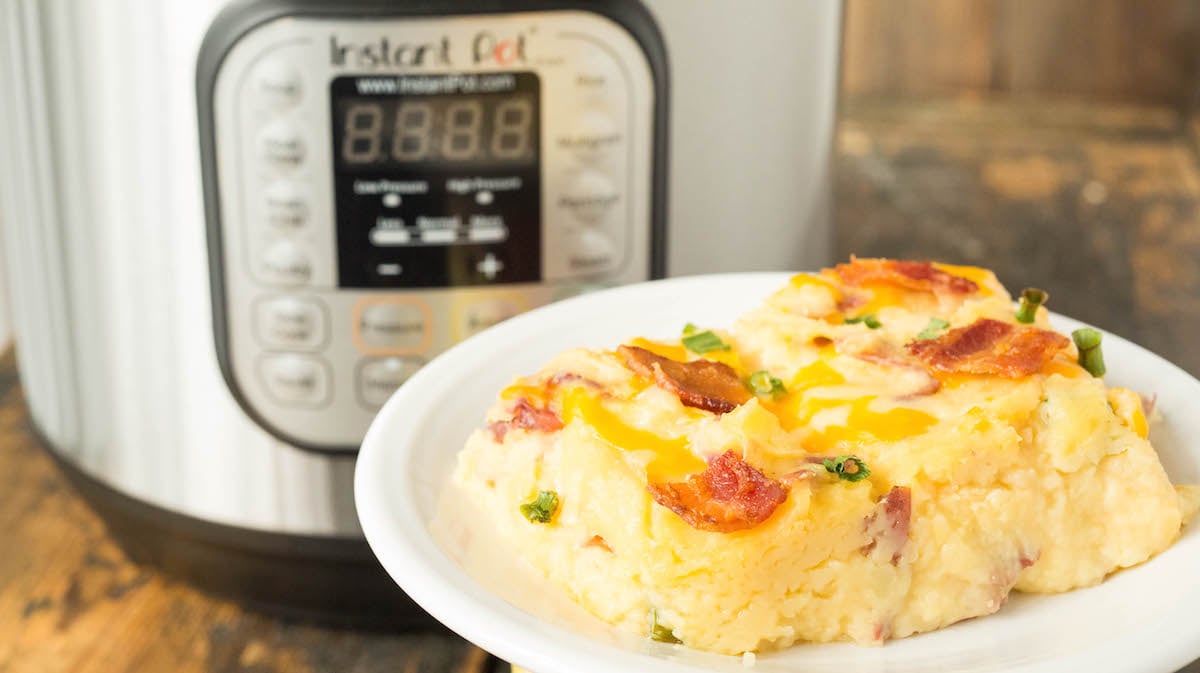 A square slice of Instant Pot Twice Baked Potato Casserole sitting in front of the Instant Pot.