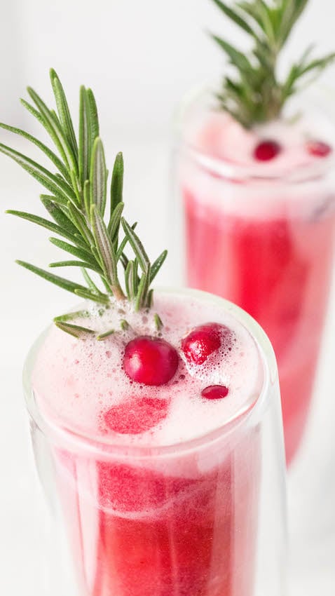 Close up of Christmas Rosé Mimosas with Cranberry Sorbet garnished with rosemary and fresh cranberries.