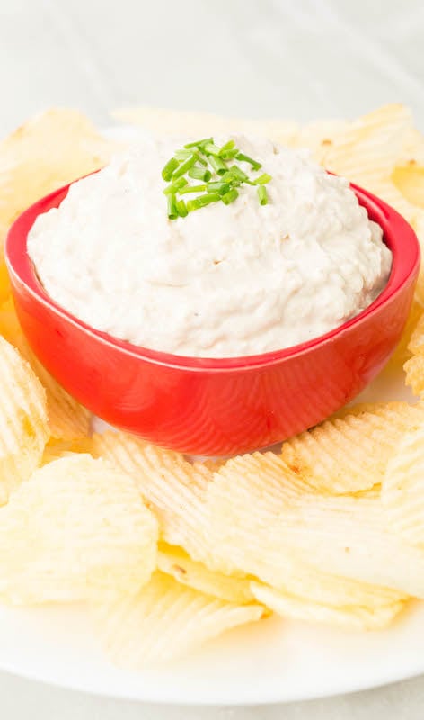 Instant Pot Caramelized Onion Dip garnished with chives and surrounded by wavy potato chips.